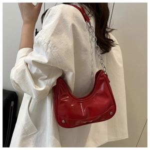 Close-up of red glossy hobo bag featuring silver chain strap and metal rivet details