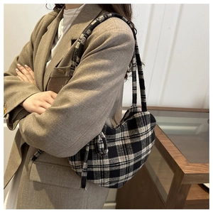 Gros plan détaillé d'un sac hobo vintage à carreaux beige et noir porté par un mannequin
