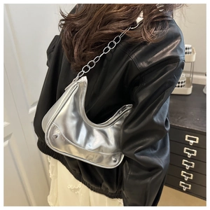 Macro detail of silver metallic crescent bag with chunky chain strap and rivet accents
