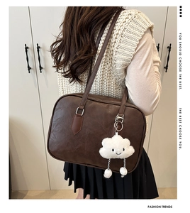 Detail view of dark brown retro shoulder bag with a cute white cloud plush pendant