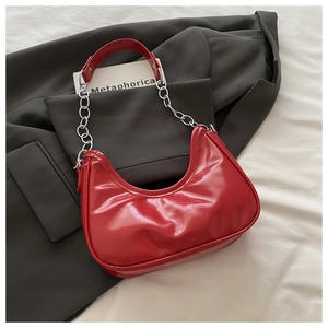 Close-up of red crescent bag featuring pleated texture and elegant metal chain strap