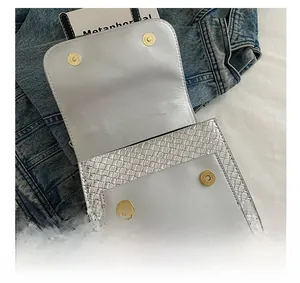 Detail of silver woven texture bag with magnetic gold buckle on denim fabric