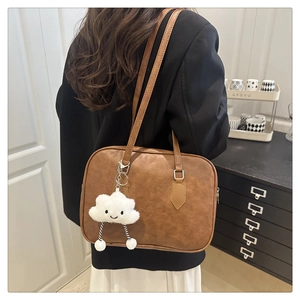 Detail of vintage brown leather bowling bag with cute plush cloud charm on a strap