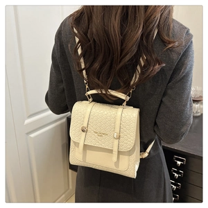 Dettaglio di un mini zaino beige minimalista con trama intrecciata e fibbie in metallo