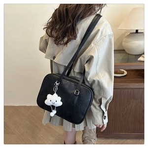 Minimalist black leather shoulder bag styled with a white cloud-shaped plush pendant