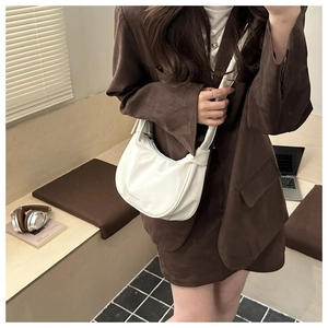 Detail of a creamy white half-moon shoulder bag with sleek leather texture and zipper close