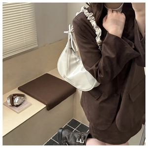 Close-up of cream white half-moon bag featuring elegant ruffled shoulder strap details