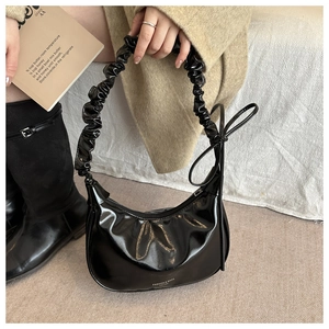 Détail du sac croissant en cuir verni noir avec poignée froncée et nœud latéral