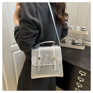 Detail of silver faux leather crossbody bag with square texture and golden fasteners