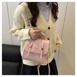 Detailed view of a pink crossbody bag with quilted pattern and gold studs on a model