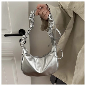 Detail of silver pleated crescent bag with metallic finish and bow ribbon accents
