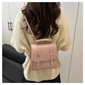 Détail d'un mini sac à dos rose en cuir tressé avec boucle métallique dorée ronde