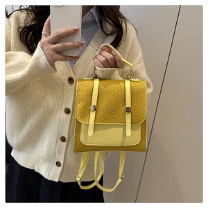 Détail d'un mini sac à dos jaune avec texture crocodile et boucle ronde métallique