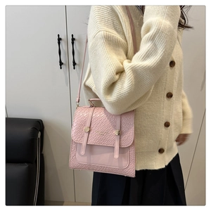 Detail of pink croc-embossed crossbody bag with stylish straps and metal buckle on top
