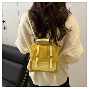 Détail macro d'un mini sac à dos jaune à motif crocodile avec boucle métallique et lanières