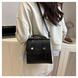 Detail of black woven texture handbag featuring metal buckles and tidal current logo