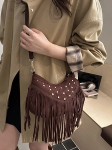 Brown suede bohemian crossbody bag with fringe tassels and gold studs on green trench coat