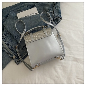 Détail du sac à dos en PU gris argenté avec rabat tissé et boucles dorées