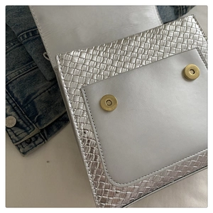 Détail du sac argenté tressé avec double fermeture à boutons magnétiques dorés