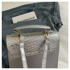 Détail du sac bandoulière argenté avec texture tissée, crochet en métal et fine sangle