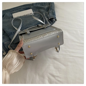Détail du fond d'un sac argenté avec pieds métalliques dorés et texture croco