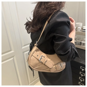 Detailed view of beige crescent underarm bag with silver buckles on a black blazer