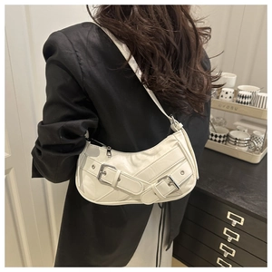 Close-up of white crescent shoulder bag featuring vintage silver buckles and metal eyelets