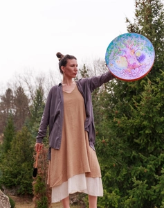 Detailed view of Tree of Life shamanic drum held by a person in a natural outdoor setting