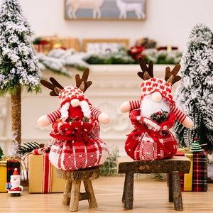 Detail view of plush Christmas reindeer dolls in red plaid drawstring gift bags on mini benches