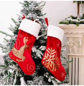 Detail of red velvet Christmas stockings with gold sequin reindeer and snowflake patterns