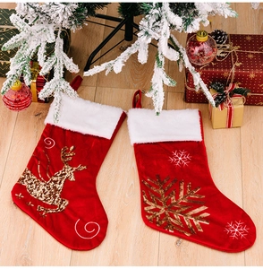Close-up of red velvet Christmas stockings with golden sequin reindeer and snowflake details