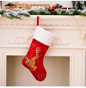 Detail of red Christmas stocking with golden sequin reindeer hanging on white fireplace