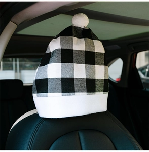 Detail of Christmas buffalo plaid car headrest cover with white pompom and plush trim
