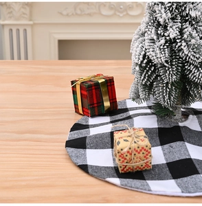 Detailed close-up of a black and white buffalo plaid mini Christmas tree skirt on a table