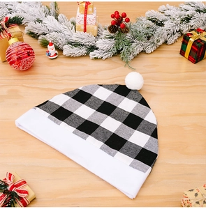 Close-up of black and white buffalo plaid Christmas hat with plush trim on festive wood background