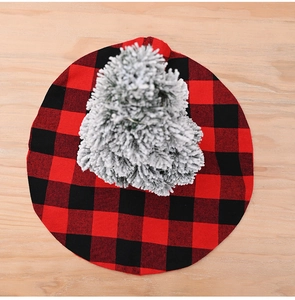 Top view of a red and black buffalo plaid mini Christmas tree skirt on a wood background