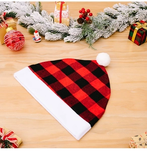 Detail of red and black buffalo plaid Christmas hat with white plush pom and snowy pine decor