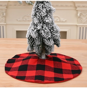 Close-up of a red and black buffalo plaid mini tree skirt under a flocked Christmas tree