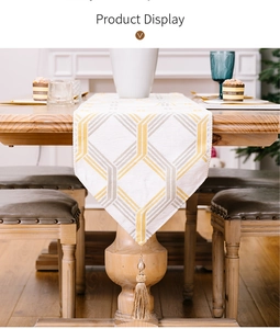 Detail of white table runner with gold and grey geometric stripes and elegant tassels