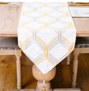 Detail of white table runner with gold grey stripes and decorative corner tassels