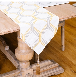 Detail of white table runner with gold and grey stripes featuring decorative tassels