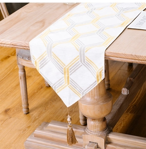 Close-up of modern table runner with yellow and gray geometric patterns and tassel detail