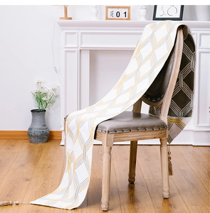 Detail of white table runner with gold grey geometric pattern and elegant fringe tassels