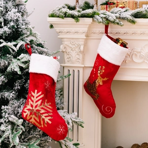 Red velvet Christmas stockings with gold sequin reindeer and snowflake embroidery hanging