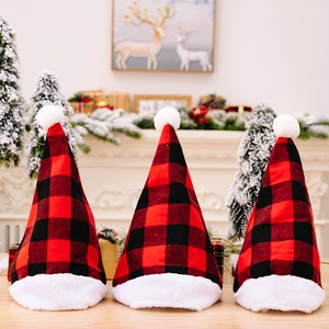 Three red and black buffalo plaid Christmas hats with white plush trim on a wooden table