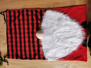 Macro detail of Christmas gnome gift bag with plush beard and red plaid drawstring