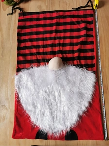 Large Christmas gnome gift bag with buffalo plaid and plush beard on wood background