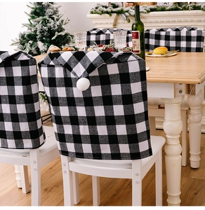 Détail de housses de chaise de Noël à carreaux noir et blanc avec pompons dans un décor festif
