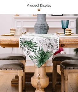 Detail of table runner with green palm leaves, white flowers and golden tassels