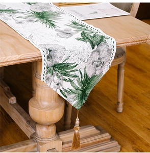 Detail of botanical leaf print on cotton linen table runner with elegant beaded tassel